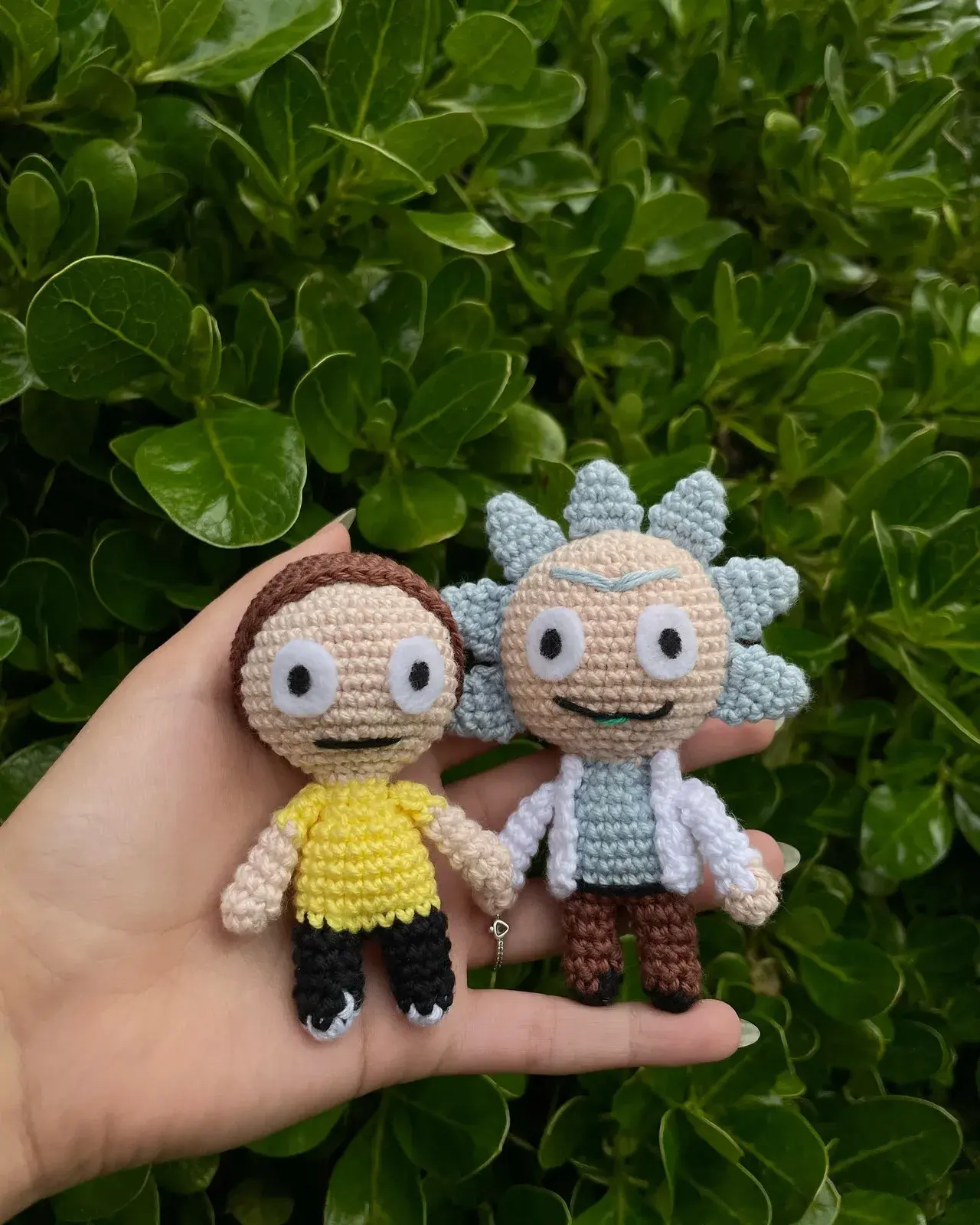 Amigurumis de Rick y Morty tomados de la mano, sobre la palma